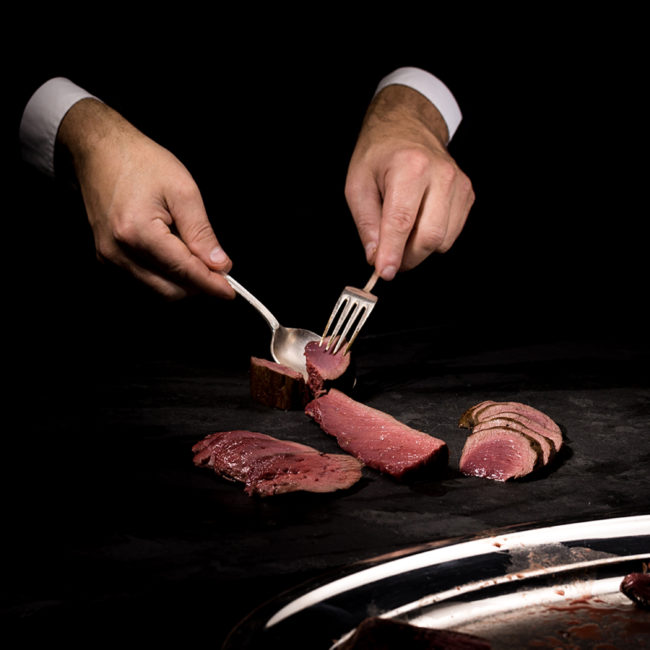 Devant les convives, Esteban Valle réalise la découpe de la selle de chevreuil avec précision et élégance. Un geste maîtrisé qui perpétue l’art du service à la française, pour une expérience gastronomique inoubliable.