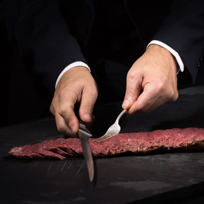 Devant les convives, Esteban Valle réalise la découpe de la selle de chevreuil avec précision et élégance. Un geste maîtrisé qui perpétue l’art du service à la française, pour une expérience gastronomique inoubliable.